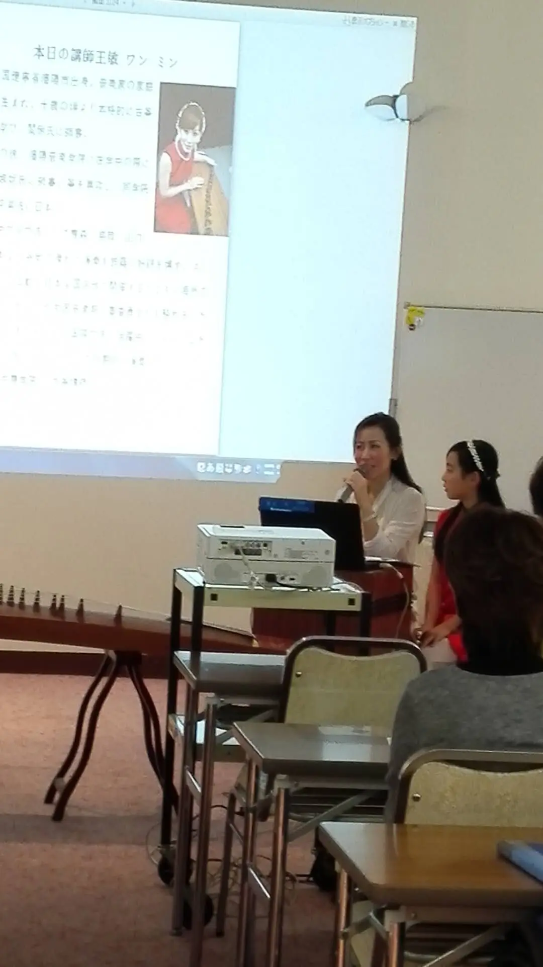 学校でのレクチャー風景。講師紹介スライドの前で講義